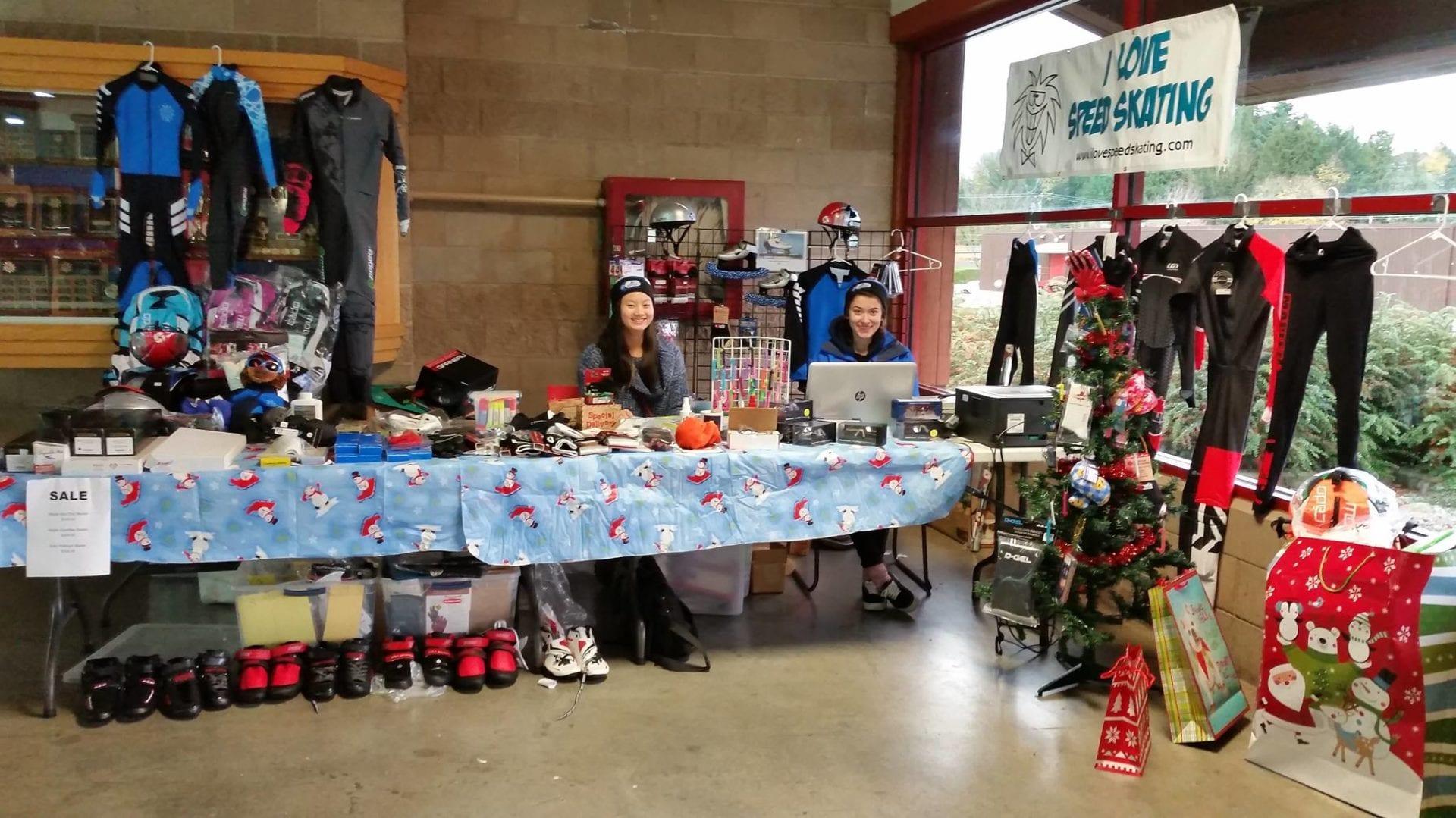 The I Love Speed Skating sales table at a rink, with skinsuits, boots and helmets on display